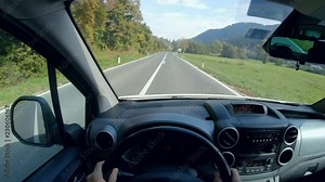 Person POV of driving car in countryside 4K. Driver point of view behind the car wheel in focus while cruising on the road in nature.