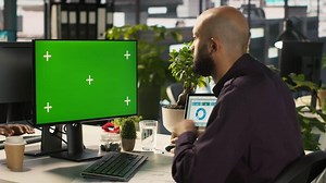 Employee at work using isolated screen PC to check progress done on customer commissioned project. Office clerk in front of mockup computer reading data statistics on paperwork after audit, camera A