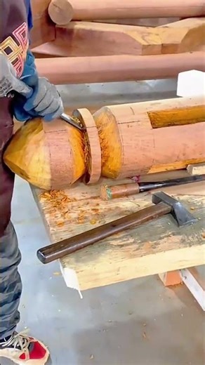 smoothing the surface of a wide and thick dark wooden plank using a sharp metal hand scraper