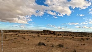Abandoned trailer cabin in the Mojave Desert by Cache Creek full of muddy water after a storm - aerial flyover