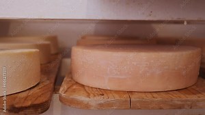 Cheese wheels maturing on shelves - in various stages of ripening, camera slide