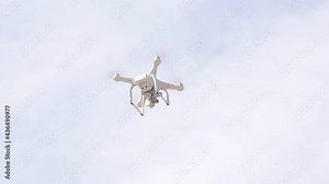 Single modern camera drone hovering, flying, seen from below, object closeup Filming drone up in the air detail shot up close, nobody, drone photography, filmmaking, drone laws concept, sky background