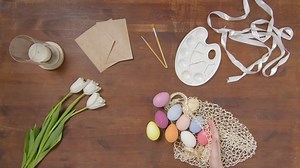 Top view of a table with items to create a composition for Easter. Women's hands put Easter eggs on the table. Church holiday-Easter