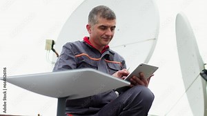 A Starlink dish is installed for a satellite signal on the roof of an office building. Engineer configuring communication with satellites
