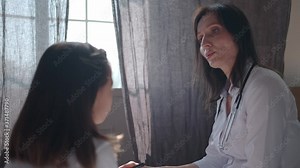 Attentive female doctor examines the girl and asks questions