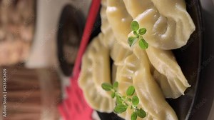 Dim sum. Homemade Chinese dumplings are served on a black plate. They eat with chopsticks. Oriental cuisine, light snacks for a traditional lunch. vertical video