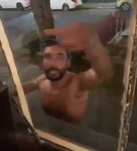 Angry man smashes restaurant window and cuts his arm.