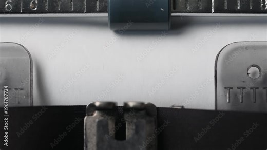 Close view of typewriter keys showing letters and numbers with paper ready for typing in a workspace setting.