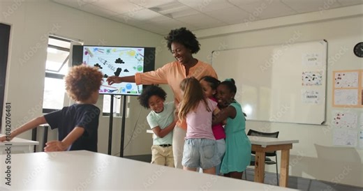 Teacher and students in classroom pointing at screen, child running in, children hugging for hug