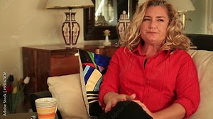 Woman seated on a sofa taking asthma treatment with inhaler