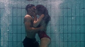 playful couple kissing underwater in swimming pool young people enjoy romantic kiss passionate lovers submerged in water floating with bubbles enjoying romance