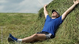 Man lying on a haystack, stretching oneself, breathing deep