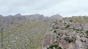 Rocky mountains dron 4K video. Aerial view mountain rocky ridges with cliffs, peaks on which grows grass and bushes in a beautiful landscape.