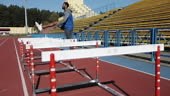 Afro-american male model runs with obstacles in the stadium. Workout...