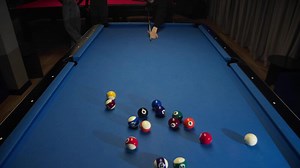 An American pool player smashes multicolored balls lying in shape of pyramid on blue billiard table with well-aimed and strong blow