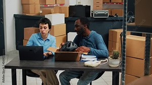 Small business partners packing merchandise in boxes and doing products quality control before shipping goods. Young woman signing logistics papers and man putting stock in packages.