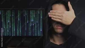 portrait of an anonymous hacker in a hood with a closed face in a dark room, at binary code background