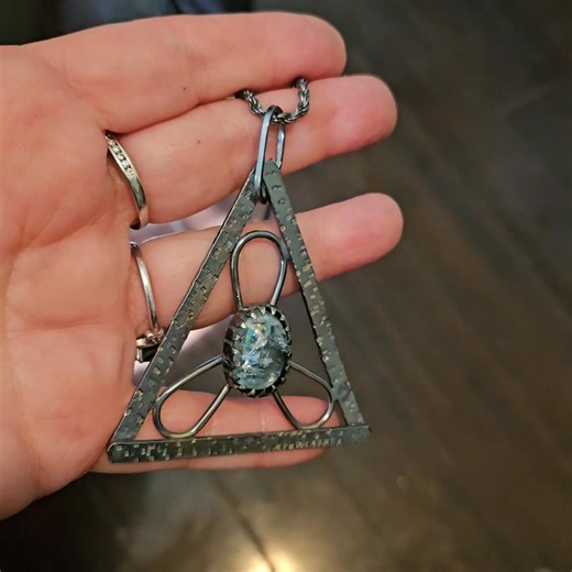 "Nordic Ice" Pretty as the frozen north, fierce as the sea beneath it. This one of a kind pendant, captures the raw beauty of winter in sterling silver and a storm-swirled 7 carat aquamarine. The hand-textured triangular frame reflects the rugged geometry of ice and mountain, while the gem’s pale blue heart glows like frozen light. A piece for those who carry calm and power in equal measure. ✨ 7 ct included aquamarine ✨ Brutalist triangle design ✨ Solid sterling silver, handmade Handcrafted with