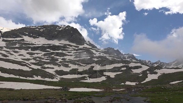 Timelapse clouds drift above snow patches on Rocky Mountains, spring alpine meadow, USA. Fast moving sky rolls past rugged ridges and green grassland as melting drifts fade in america. mountain meadow, highland grassland Stock Video Footage - Alamy