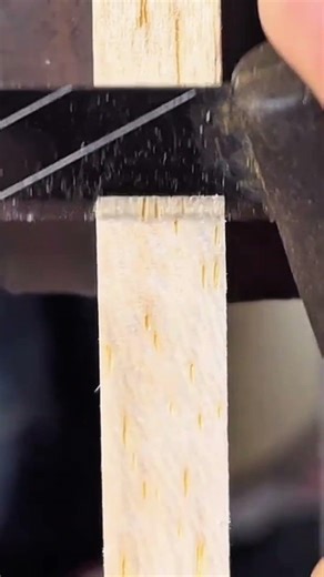 cutting through a wooden board using a small hand saw to create multiple pieces for a woodworking