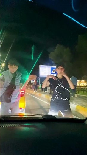 children dancing in front of a car on the street