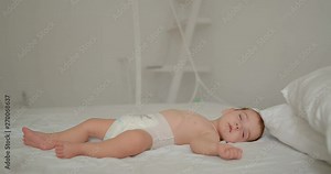 six month old baby sleeps quietly in the big bed. tracking shot. in slow motion