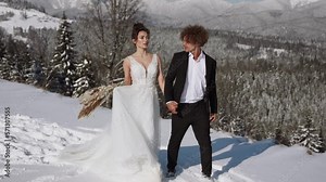 Beautiful wedding couple. Winter wedding in the mountains covered with snow of the groom in a beautiful suit and the bride in a beautiful wedding dress.Сoncept of a winter wedding