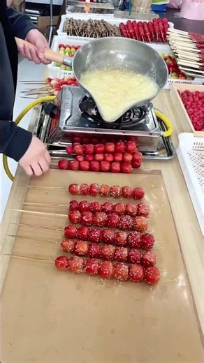 the process of making tanghulu from berries that are dipped in liquid sugar and then left to harden