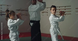 Cinematic shot of budokai fighter master and his pupils practicing Aikido training in modern Japanese martial arts school. Concept of healthy lifestyle, sports, recreation, defence, religious beliefs.