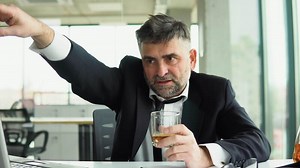 Angry drunk senior boss with glass of whiskey shouts at the camera to the employee. Old director dismisses the employee