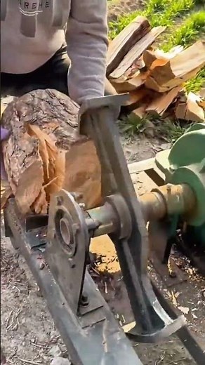 splitting a thick wooden log into firewood pieces using a heavy mechanical rotary log splitter