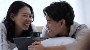 LGBTQ couple using digital device in the bedroom