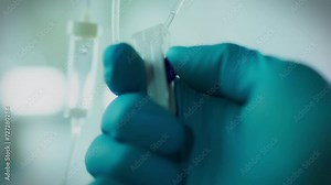 In the operating room. An anesthesiologist wearing protective gloves adjusts the IV drip. Young professional focusing on IV drip installation using advanced technology