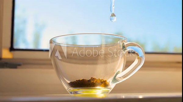 Pour boiled water into a cup of coffee. Steam the coffee with water in slow motion. Instant coffee in a transparent cup