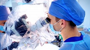 Surgeon using operating microscope. Doctor performing surgery with microscope