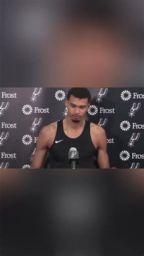 Victor Wembanyama moves the Gatorade drink off the table during a press conference | NBA