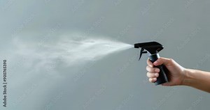 Hand-held spray bottle misting a shiny surface, demonstrating effective cleaning methods. Cleaning company. Copyspace