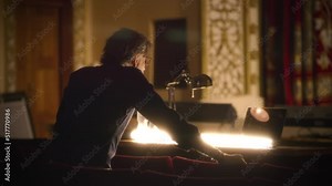 A performance director with script standing in rows of chairs near the table in a dim theater and controling a rehearsal Stock Video
