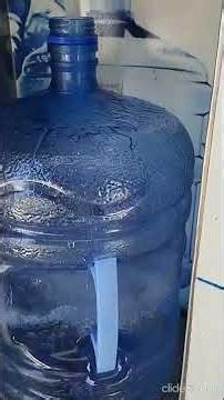 REFILLING THE WATER JUG AT THE PURIFIED WATER MACHINE