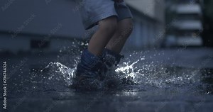 Child in rain boots leaping joyfully in puddle with ultra slow-motion capture, nostalgic childhood concept