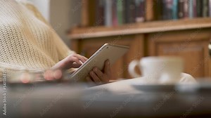 Woman hands holding silver iPad in her hands. She is scrolling, touching screen of the device with her fingers. Browsing web pages on the internet, reading news, checking her favourite apps.