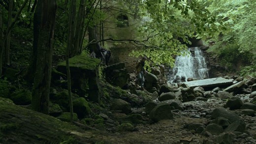 Man walks through jungle near a waterfall - Free Stock Video