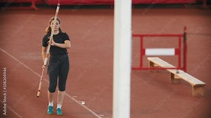 Pole vault training on the stadium - woman running up and jumping over the bar touching it