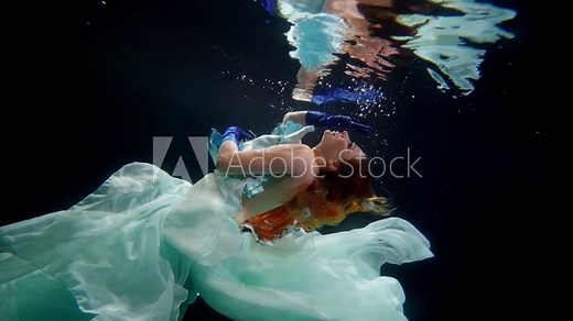 gorgeous redhead woman floating in mysterious depth of magical sea, underwater shot