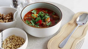 Traditional Hungarian dish, goulash, slow-cooked with beef, potatoes, carrot, tomatoes, paprika, onion and bell peppers. White bowl on wooden table.