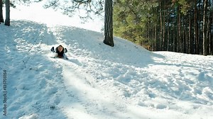 happy child moves down on a sled backlit in sunlight, Boy sledding down the hills, sleigh ride through the snow, fast descent on a snowy slope in the woods, fun winter holidays,
