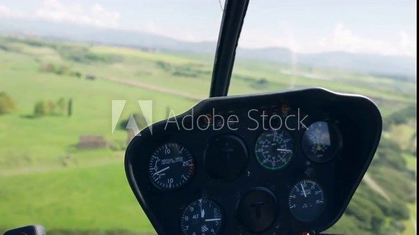 View from inside of flying helicopter, control panel inside the helicopter cabin with different commands and navigation instruments, blurred countryside panoramic view from flying helicopter