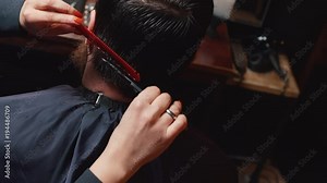 woman barber shearing a young man in a barbershop, close-up