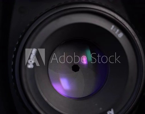 Close-up footage of aperture adjusting in a camera: diaphragm blades of a fixed lens closing and opening.