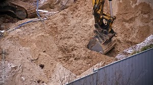 Construction Site Excavator Scooping Dirt Creating Excavation for Concrete Foundation
